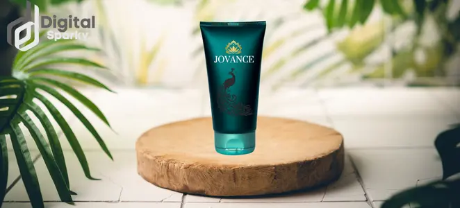 "A teal product tube labeled 'JOVANCE' with a peacock design, on a wooden display block surrounded by green foliage, with the Digital Sparky logo.