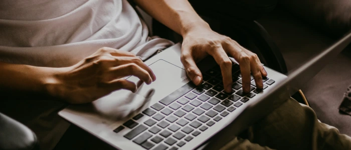 Close-up of hands typing on a laptop keyboard.